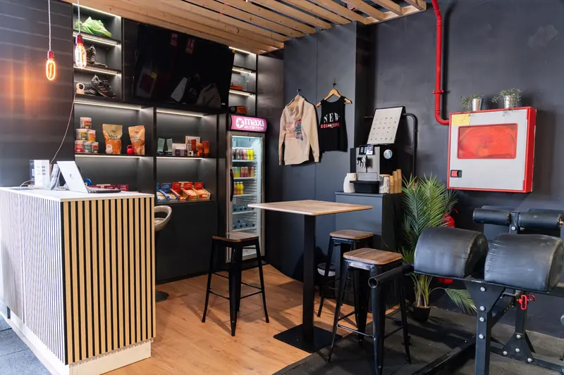 Recepción y coffee corner con barra de madera y nevera