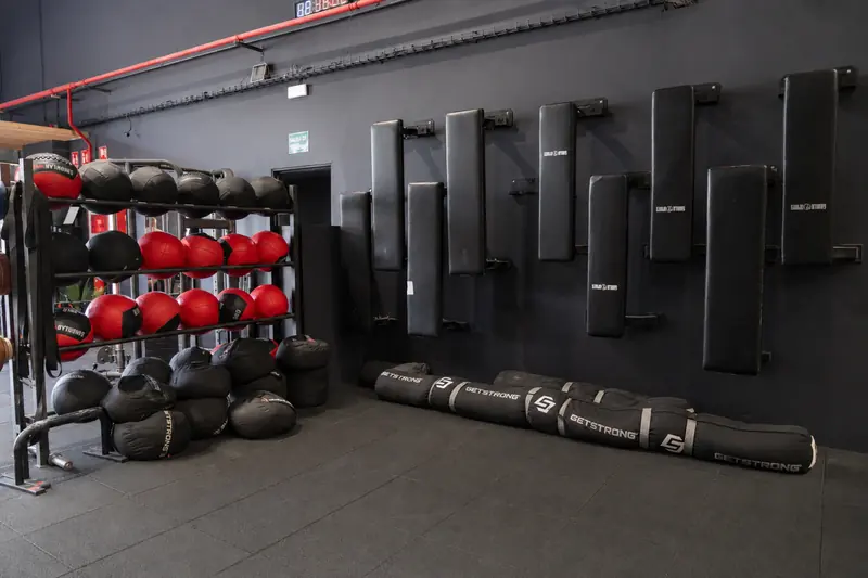 Pared del box con bancos, balones medicinales y sacos de arena